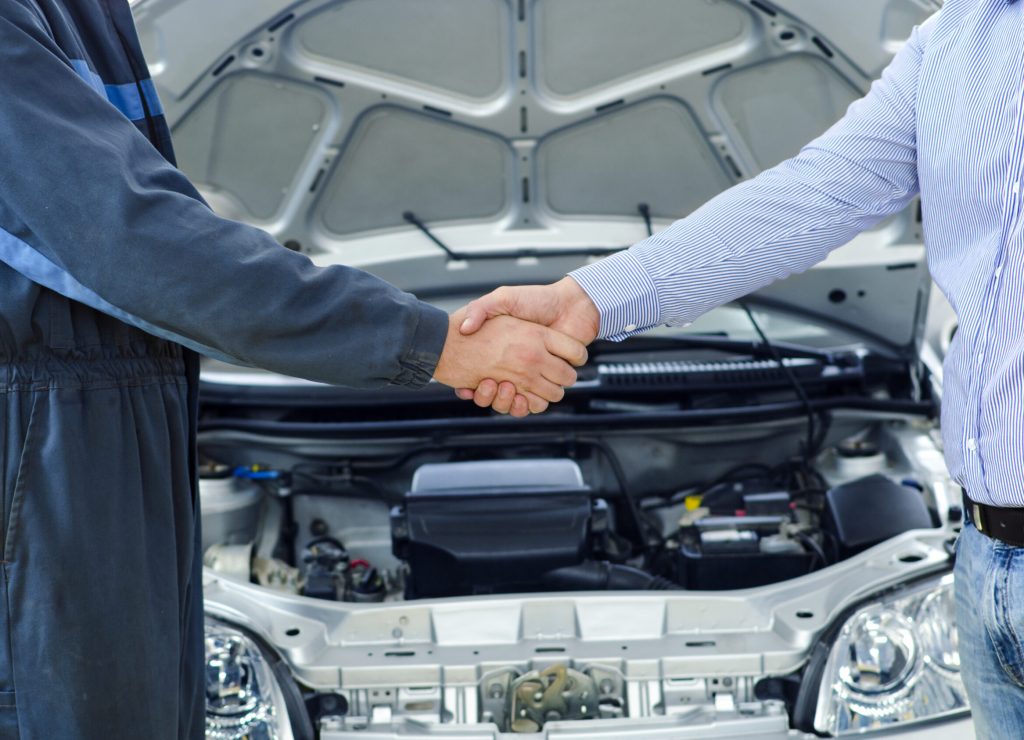 Car mechanic and customer shaking hands.